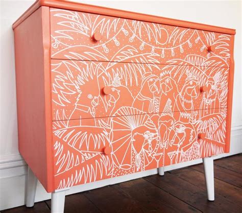 an orange and white painted dresser on wooden floor next to wall with wood floors in room