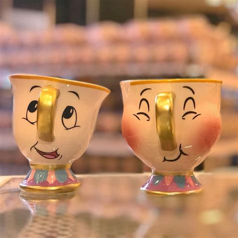 two coffee cups with faces painted on them sitting on a glass table in ...