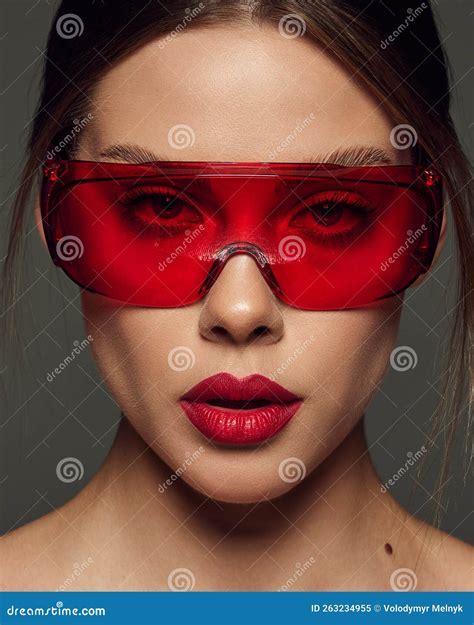 Close-up Portrait of Beautiful Young Woman with Red Lipstick Posing in Red Plastic Glasses Over ...