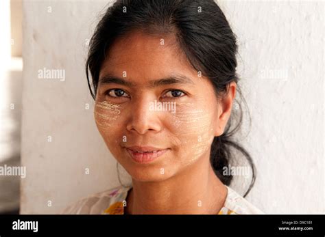 Portrait of a pretty Burmese woman with face covered in thanakha sandalwood paste as makeup ...