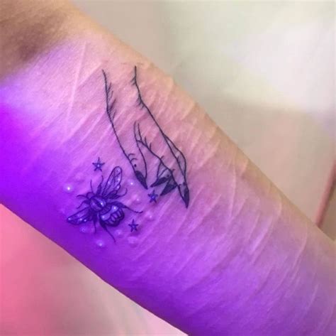a small tattoo on the arm of a woman with flowers and stars around her wrist