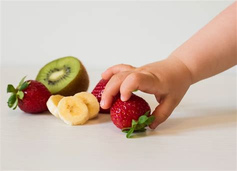 Premium Photo | Baby hand picking fruits