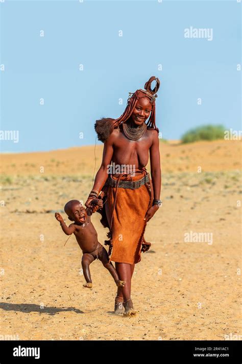 Himba woman is carrying her child, holding his hand Stock Photo - Alamy