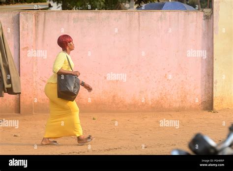 OUIDAH, BENIN - Jan 10, 2017: Unidentified Beninese woman in yellow dress walks on the street ...