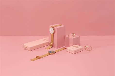 three watches and two boxes on a pink background