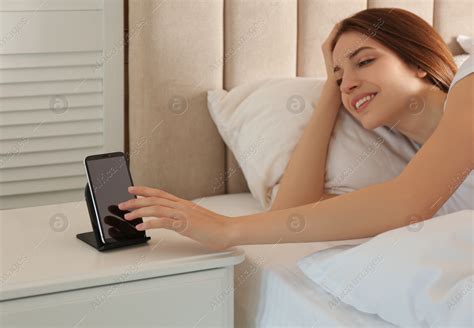 Woman taking smartphone from wireless charger in bedroom: Stock Photo | Download on Africa ...