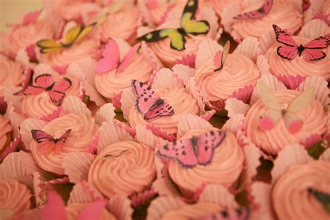 cupcakes with pink frosting and butterflies on them are arranged in a pile