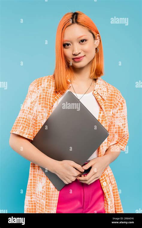 positive emotion, happy face, young asian woman with dyed red hair standing with laptop and ...