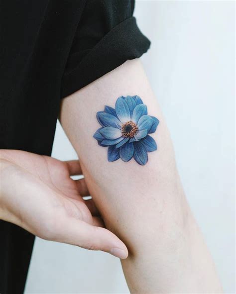 Blue dahlia flower tattooed on the inner arm,