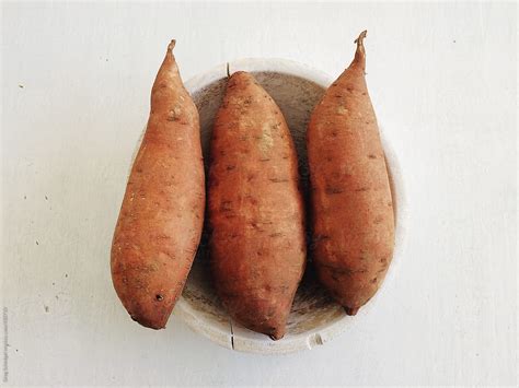 "Three Delicious Yam Sweet Potatoes In A Bowl On A White Kitchen Table" by Stocksy Contributor ...