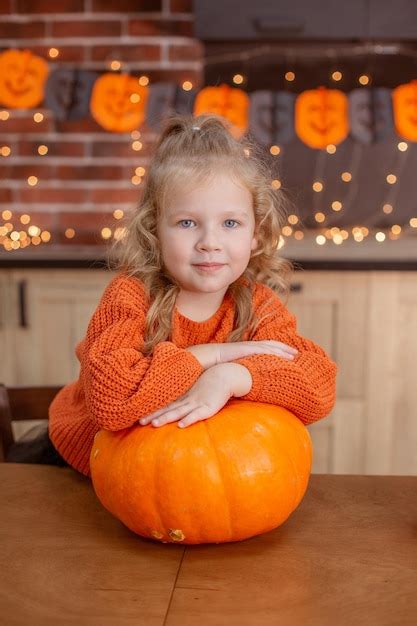 Premium Photo | Little girl at home in the kitchen at the table with a pumpkin for halloween