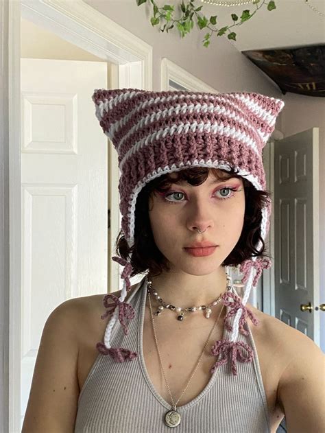 a woman wearing a knitted cat hat with beads on her neck and necklace around her neck