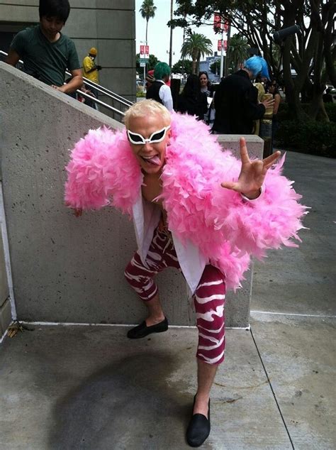 a man dressed in pink and white is posing for the camera with his hands up