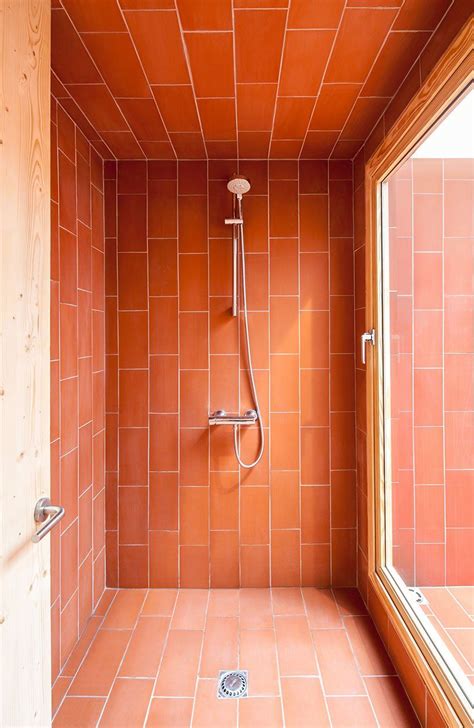 an orange tiled bathroom with a shower and window