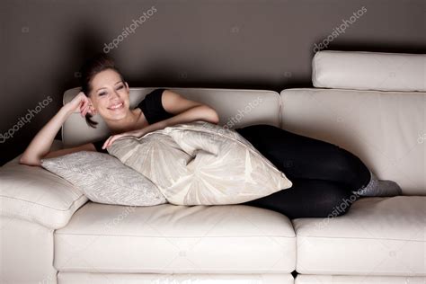 A happy young woman watching TV, lying on the couch comfortably — Stock ...