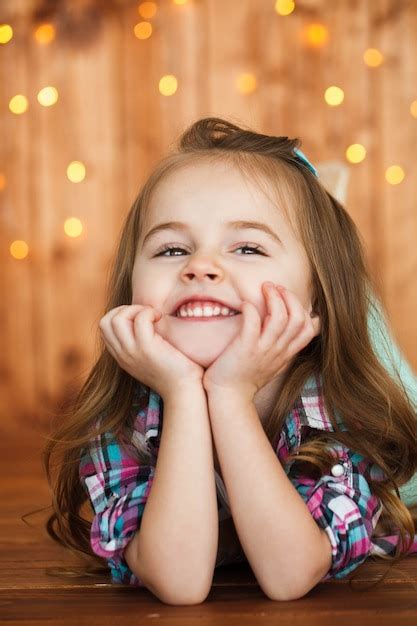 Free Photo | Dreamy little girl lies on wooden floor and holds her chin ...