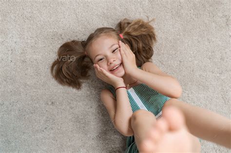 Relaxed little girl lying on the floor indoors and smiling Stock Photo ...