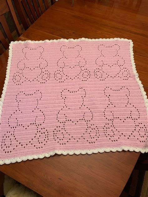 a pink crocheted placemat sitting on top of a wooden dining room table