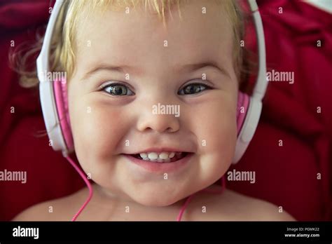Beautiful baby in baby carriage playing with earphones unplugged Stock Photo - Alamy