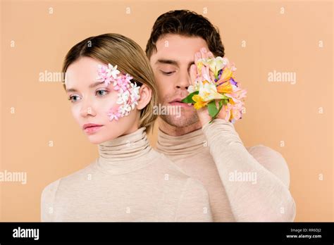 handsome man with alstroemeria flowers on hand covering one eye near beautiful girlfriend ...