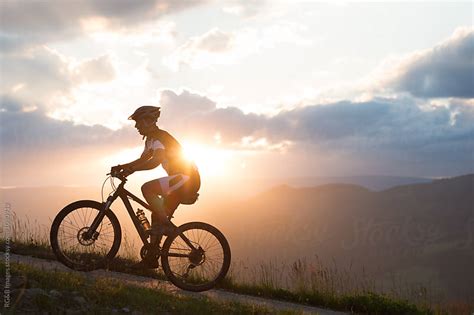 Man riding a bike uphill against sunset sky - Stock Image - Everypixel