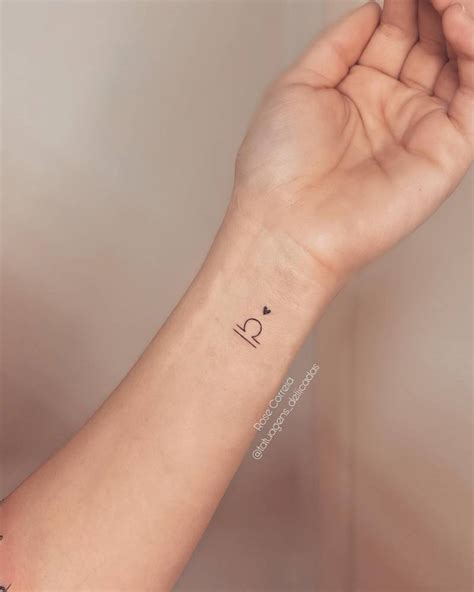 Libra symbol and tiny heart tattooed on the wrist.