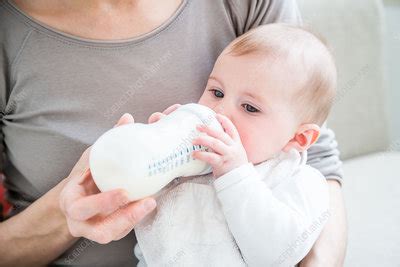 Baby girl drinking milk from a bottle - Stock Image - C035/3687 - Science Photo Library