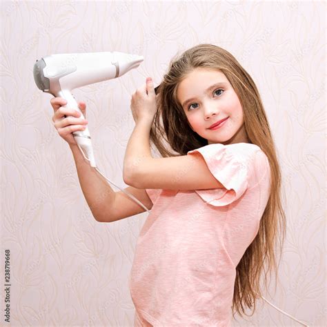 Cute smiling little girl child drying her long hair with hair dryer Stock Photo | Adobe Stock