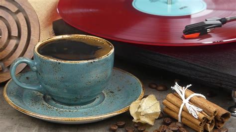 a cup of coffee sitting on top of a saucer next to some cinnamon sticks