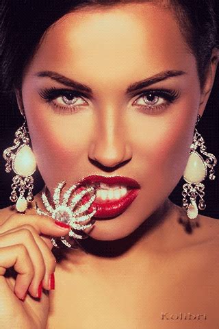 a woman with red lipstick and jewelry on her face is posing for the camera,