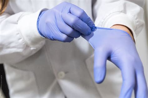 "Scientist Female Putting The Gloves In The Lab" by Stocksy Contributor "Bisual Studio" - Stocksy