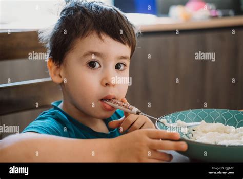 Caucasian child with brown hair eats porridge himself. Healthy breakfast. Healthy meal Stock ...