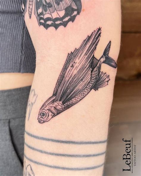 Flying fish tattoo located on the elbow.