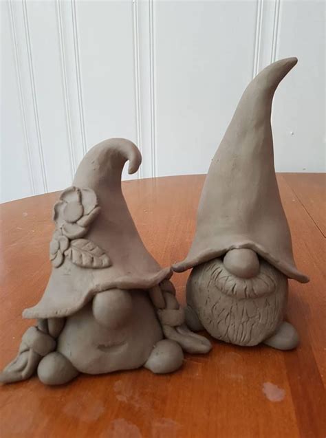 two clay gnomes sitting on top of a wooden table