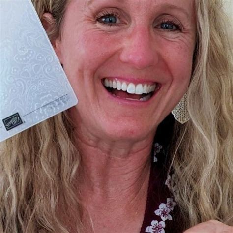 a woman holding up a white plastic card to her face and smiling at the camera