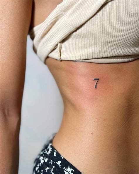 Minimalistic number "7" tattoo located on the rib.