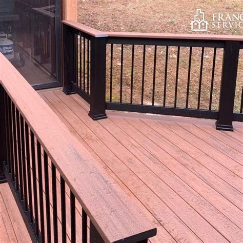 a wooden deck with black railing and glass door