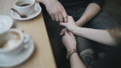 Hand-held shot of a couple holding hands in a coffee shop - Stock Video Footage - Dissolve