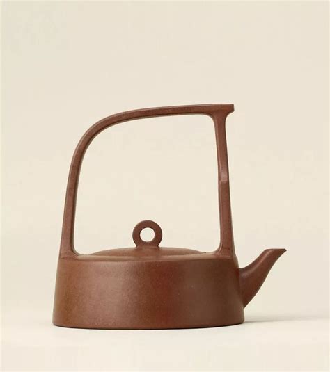 a brown tea pot with a handle on the top and bottom, sitting in front of a white background