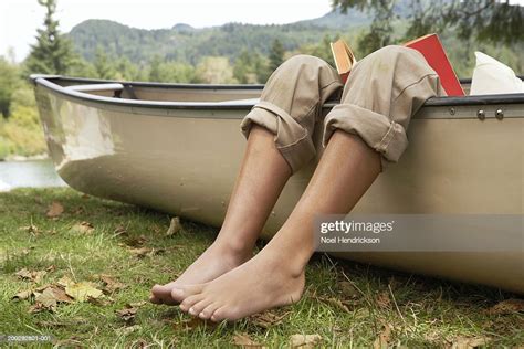 Barefoot Boy Reading Book In Canoe By Lake Low Section Closeup Of Legs Over Edge Of Canoe High ...