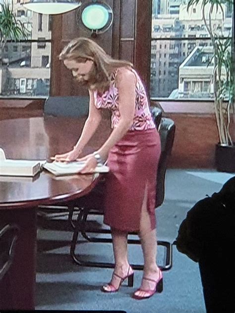 a woman standing in front of a book on top of a table next to a window