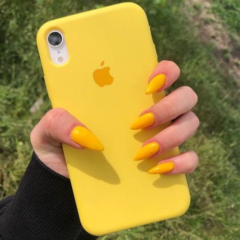 a woman's hand holding an iphone case with yellow nails