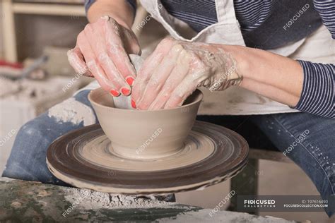 Close up of a woman's hand shaping pottery clay on a pottery wheel in a ceramic workshop ...