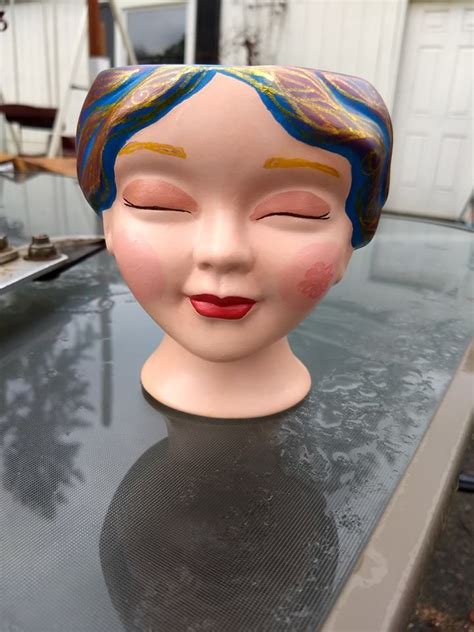 a doll head sitting on top of a table next to a garage door, with it's eyes closed