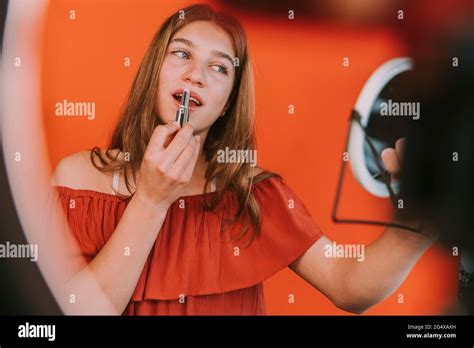 Female influencer applying lipstick while vlogging make-up tutorial at home Stock Photo - Alamy