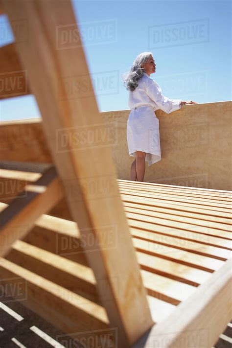 Woman looking over balcony at resort - Stock Photo - Dissolve