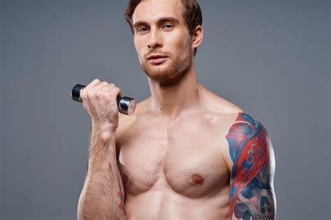 Premium Photo | Sporty male bodybuilder with pumped up arm muscles and color tattoo dumbbell ...