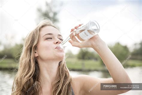 Young woman drinking water from bottle, outdoors — carefree, female - Stock Photo | #180918008