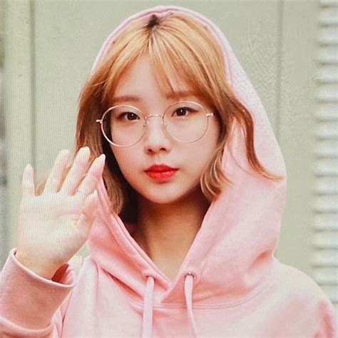 a woman wearing glasses and a pink hoodie is making the stop sign with her hand