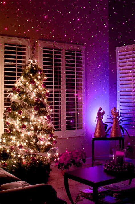 a living room with a christmas tree in the corner and purple lights on the ceiling